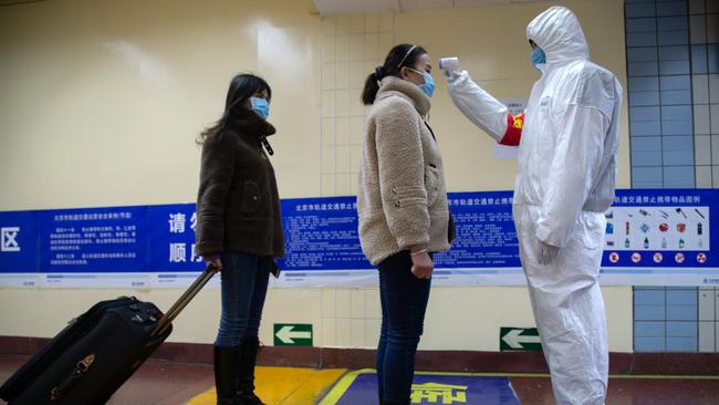 A health worker checks the temperature of women entering the subway in Beijing. Picture Betsy Joles/Getty Images