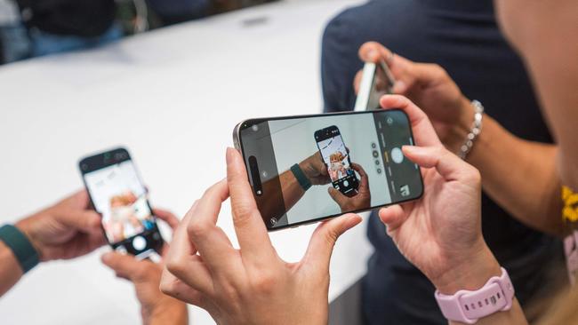 A woman takes a video of the new iPhone 16 Pro. (Photo by Nic Coury / AFP)