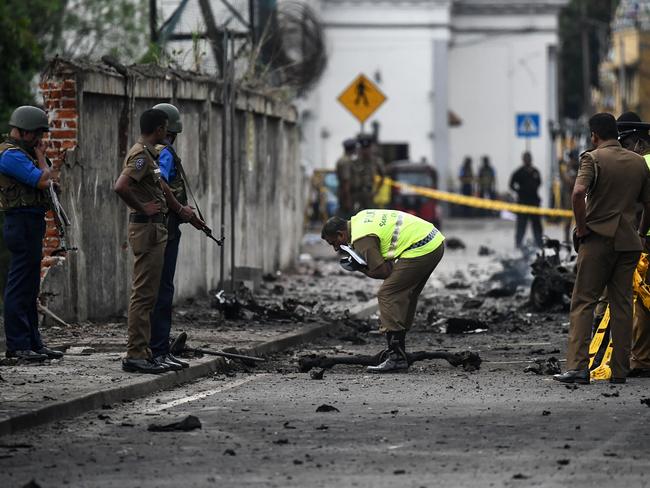 Sri Lankan security personnel inspect the debris of a car after it explodes when police tried to defuse a bomb near St Anthony's Shrine in Colombo. 