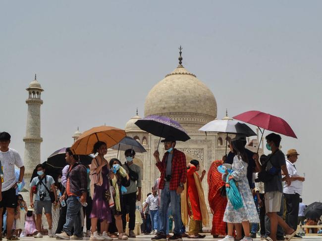 Tourists shelter from the sun under umbrellas while visiting the Taj Mahal during a hot summer day in Agra. Picture: AFP