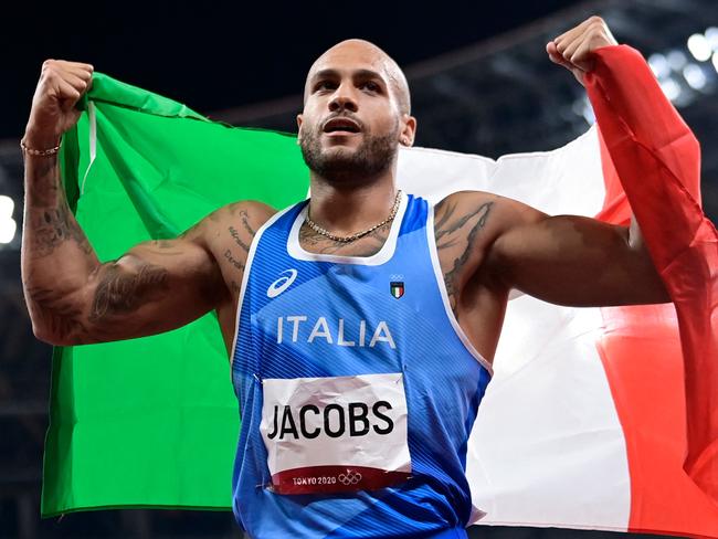 Italy's Lamont Marcell Jacobs celebrates with the flagof Italy after winning the men's 100m final during the Tokyo 2020 Olympic Games at the Olympic Stadium in Tokyo on August 1, 2021. (Photo by Javier SORIANO / AFP)