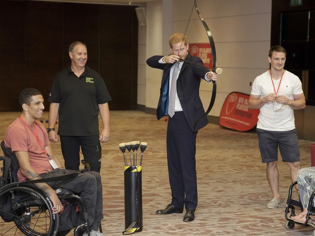 Prince Harry, Duke of Sussex tries archery as he meets Liam O-Keefe from Bristol (L) with Dani Watts from London (R) during a visit to the RFU Injured Players Foundation annual Client Forum at Twickenham Stadium on July 18, 2018 in London, England. (Photo by Tim Ireland - WPA Pool/Getty Images)
