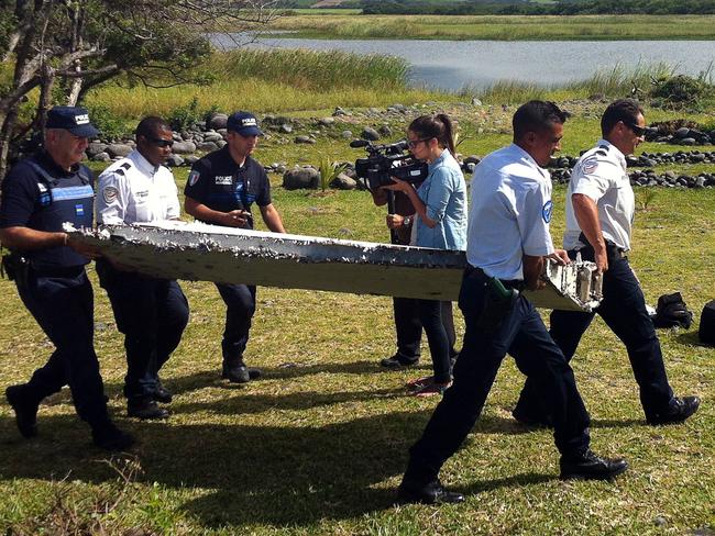 Is this it? ... Police carry a piece of debris from an unidentified aircraft found in the coastal area of Saint-Andre de la Reunion that may be MH370. Picture: AFP