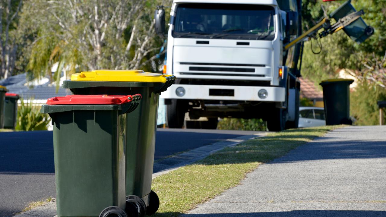 Rubbish bins with rubbish truck in background lifting a bin