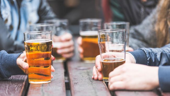 ESCAPE: UK - Aussies, Mikaella Clements.  Hands holding glasses with beer on a table at pub in London. A group of friends is enjoying beer time in the city, close up on the glasses. . Picture: iStock