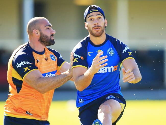 Corey Norman kicks as Tim Mannah closes in during Parramatta training.