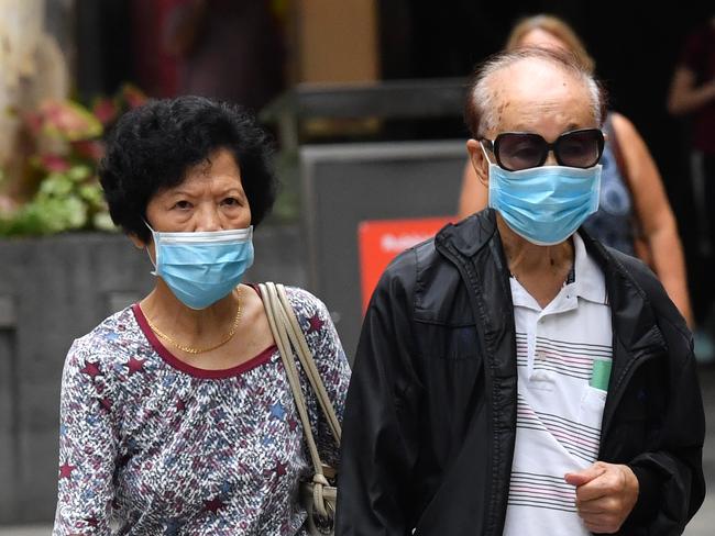 Two People wearing protective face masks are seen walking along the Queen Street Mall in Brisbane, Monday, March 23, 2020. Queensland has recorded its highest increase of coronavirus (COVID-19 ) cases in a 24-hour period, with 60 new cases, taking Queensland's total number of cases to 319. (AAP Image/Darren England) NO ARCHIVING