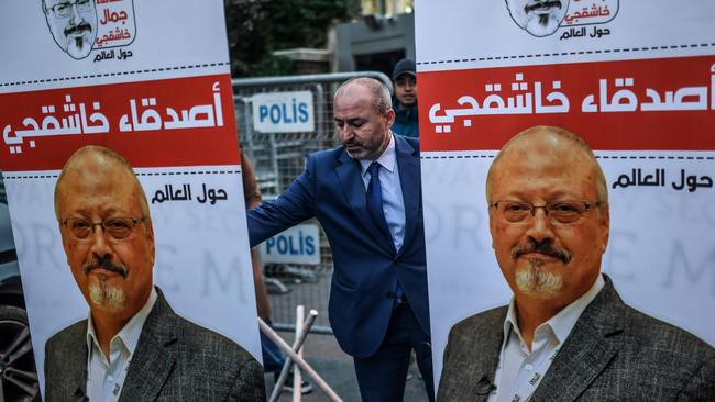 A man settles posters picturing Saudi journalist Jamal Khashoggi outside the Saudi Arabia consulate in Istanbul during a demonstration in protest of his murder. Picture: Bulent Kilic/AFP