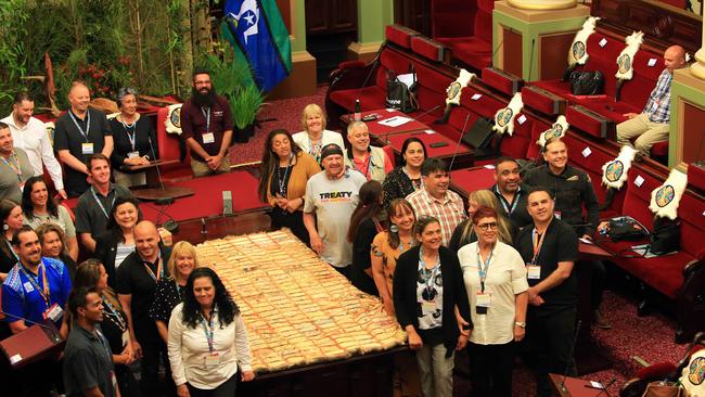 Jason Kelly remains seated as other members of the First Peoples’ Assembly stand for a group photo on Monday. Picture: Aaron Francis