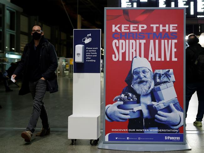 A pedestrian wearing a face mask due to the COVID-19 pandemic, walks past a Christmas-themed advert inside St Pancras International train station in central London. Picture: AFP