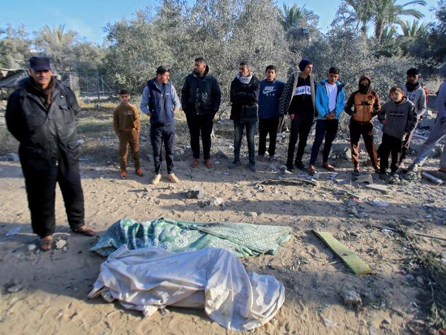 People stand over the shrouded bodies of members of the Abu Samra family who were killed in an Israeli strike on their home in Deir el-Balah in the central Gaza Strip. Picture: AFP