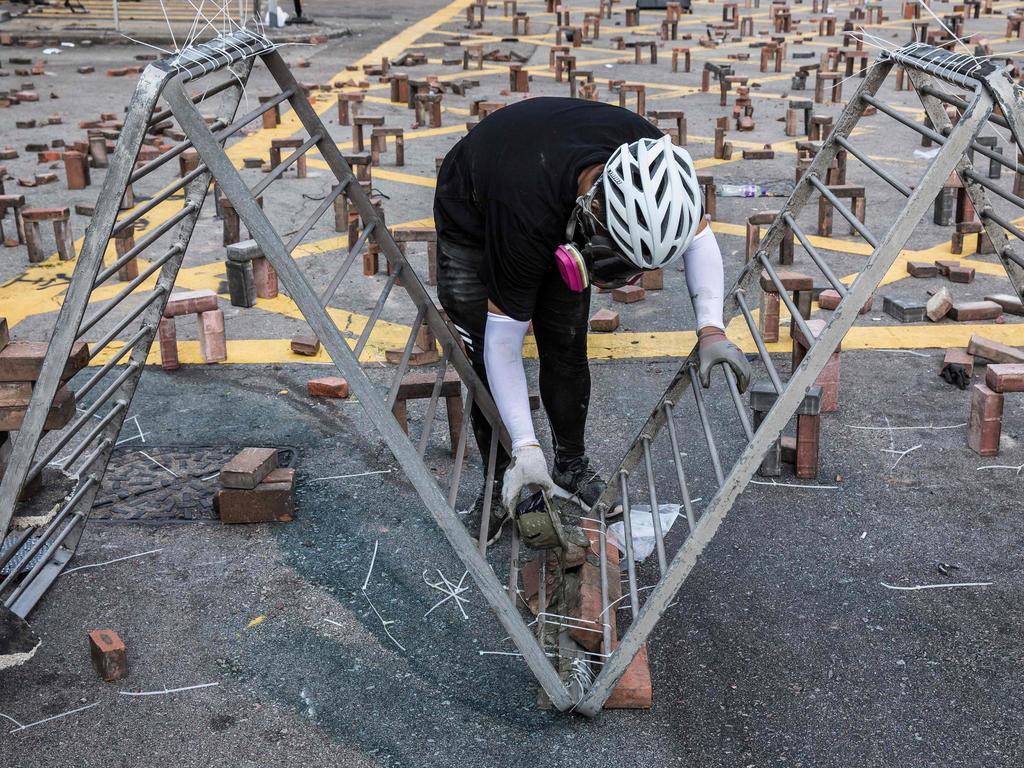 A protester pours cement onto a barricade on a street outside The Hong Kong Polytechnic University in Hong Kong. Picture: ISAAC LAWRENCE / AFP