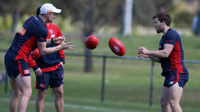 Aaron vandenBerg, left, handballs with skipper Jack Viney at training.