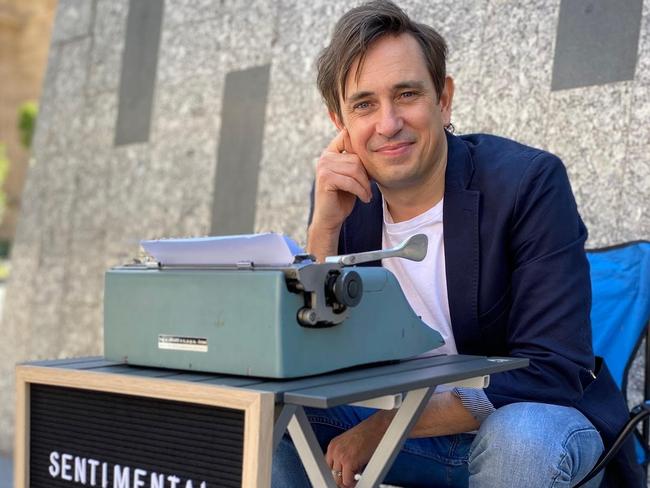 Credit: Trent Dalton with his typewriter and sign in Brisbane collecting love stories for his 2021 book, Love Stories. Picture: Fiona Franzmann