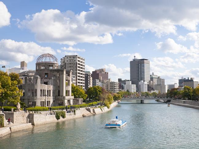 "A business man, his bicycle and cherry blossoms in the forground with the Hiroshima Atomic Bomb Dome (Gembaku Domu, formerly the Industrial Promotion Hall) in the background. The Aioi River runs between them. Overcast day.This was one of a very few buildings left standing within a two kilometer radius of the explosion. Amazing because the shock wave from the bomb created a pressure of 35 tons per square meter at the hypocenter."