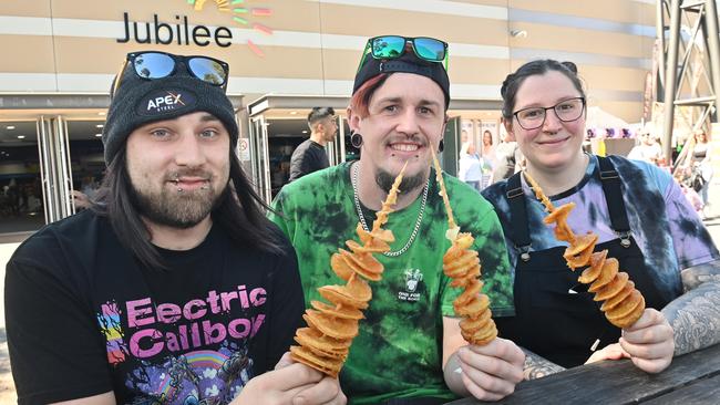 Jordan Sheridan, Brett Fridday and Charleigh Kerr dig into their chips on a stick at the Royal Adelaide Show. Picture: Keryn Stevens