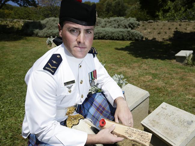 Royal Australian Air Force airman, Leading Aircraftman Robert Scott from the Royal Australian Air Force Band holds a dedication to his Great-Great Uncle, Private Tom Haylock at his gravesite. Picture: ADF