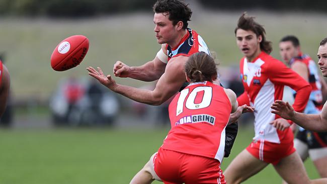 Lauderdale’s Tyler Martin feeds out a handball while being tackled by Clarence’s James Bealey. Picture: LUKE BOWDEN