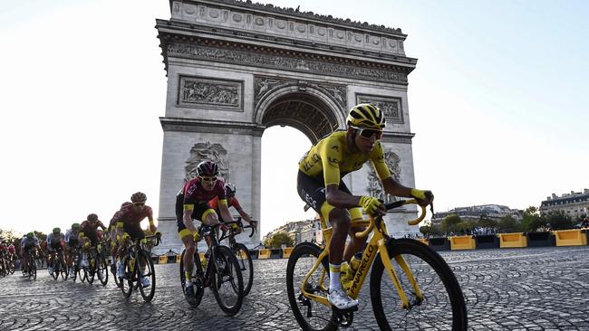 TOPSHOT – Colombia's Egan Bernal (R), wearing the overall leader's yellow jersey (C-R) and cyclists ride down the Champs Elysees avenue next to the Arc de Triomphe during the 21st and last stage of the 106th edition of the Tour de France cycling race between Rambouillet and Paris Champs-Elysees, in Paris, on July 28, 2019. (Photo by Anne-Christine POUJOULAT / AFP)