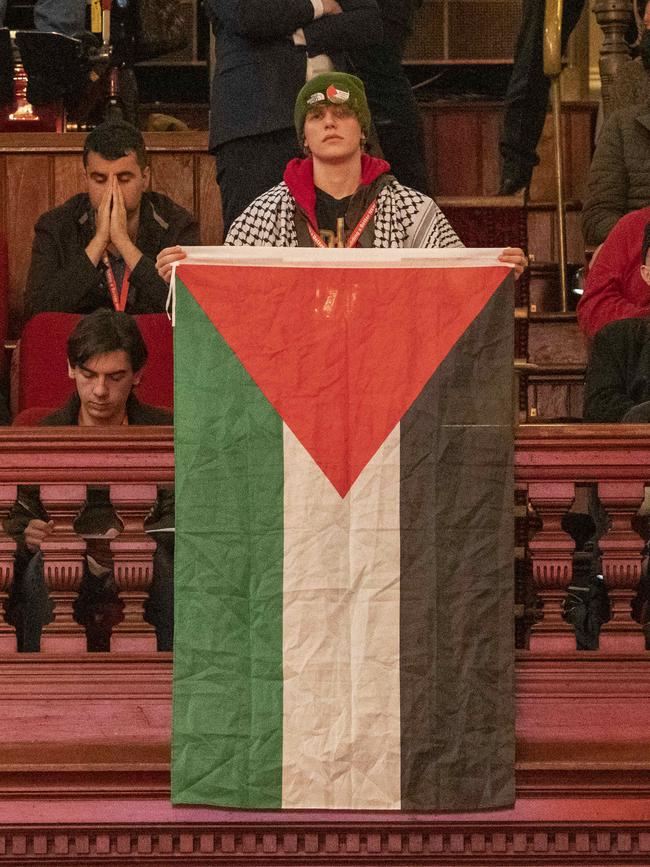 A Labor Party delegate hangs a Palestinian flag as Mr Albanese delivers his speech.