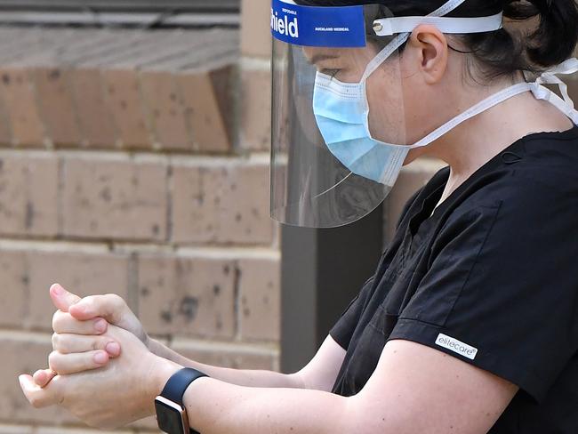 A staff member sanitises her hands outside the Menarock Life aged care facility, where a cluster of some 28 new infections had been reported, in the Melbourne suburb of Essendon on July 14, 2020, as the city battles fresh outbreaks of the COVID-19 coronavirus. - Authorities on July 13 reported 177 new infections in and around Melbourne after the Australian city imposed a six-week lockdown on July 9, with surrounding Victoria state sealed off from the rest of the country in an effort to contain the virus. (Photo by William WEST / AFP)