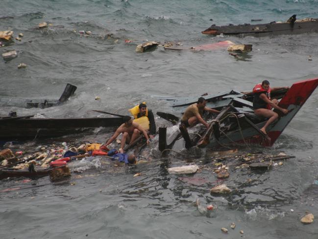 MUST CREDIT: Amy Rossbach and Allan Krepp... NEWS: Navy personel pull survivors and dead bodies from the water as they search for survivors in Flying Fish Cove after wooden fishing boat containing asylum seekers was destroyed and broke apart when it crashed into cliffs off Christmas Island. At least 28 bodies have been recovered with 42 known to have been pulled from the water alive. Pic Amy Rossbach.