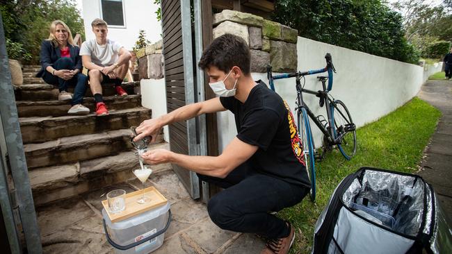 Journalist Julie Cross and her son Charlie, 18, watch as barman Luca Reigada makes cocktails on the doorstep. Picture: Julian Andrews).