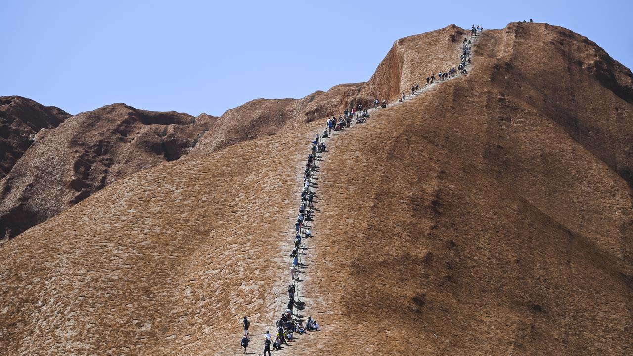 Tourists are seen climbing Uluru, also known as Ayers Rock at Uluru-Kata Tjuta National Park in the Northern Territory, Friday, October 25, 2019. Today is the last day people will be able to climb Uluru. (AAP Image/Lukas Coch) NO ARCHIVING