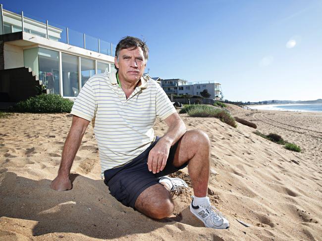 Garry Silk sits on a makeshift protective seawall a year after the historic storm undermined houses on Collaroy beach. Picture: Adam Yip