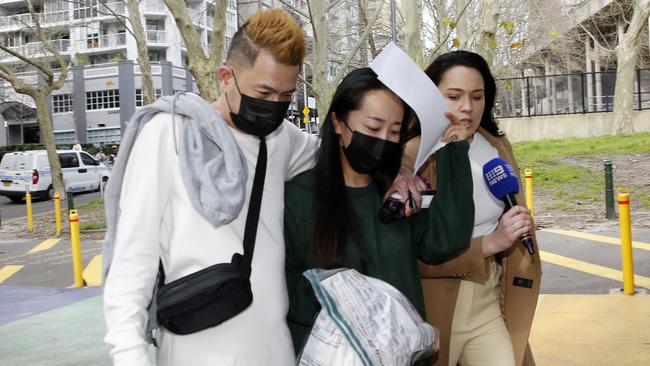 Shielding herself form cameras, Zhongfang Zhang, centre, leaves Surry Hills police station. Picture: John Appleyard