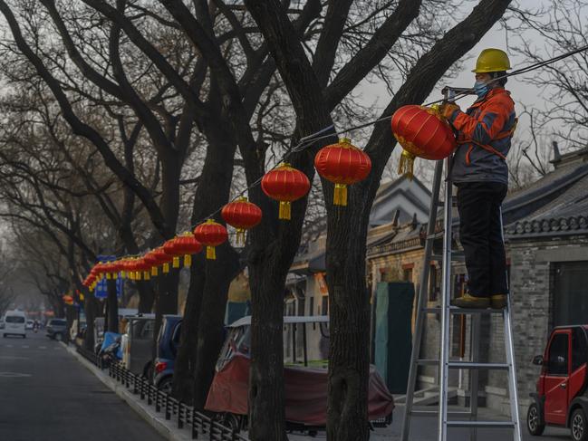 A worker hangs festive red lanterns, or hong deng long, to mark the upcoming Chinese New Year on a street on January 21, 2021 in Beijing, China. Picture: Kevin Frayer/Getty Images