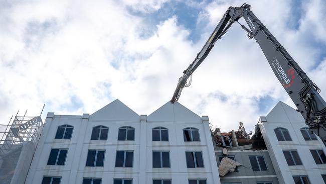 The excavator pinches the top of the Novotel building, preparing to tear down another piece of it.