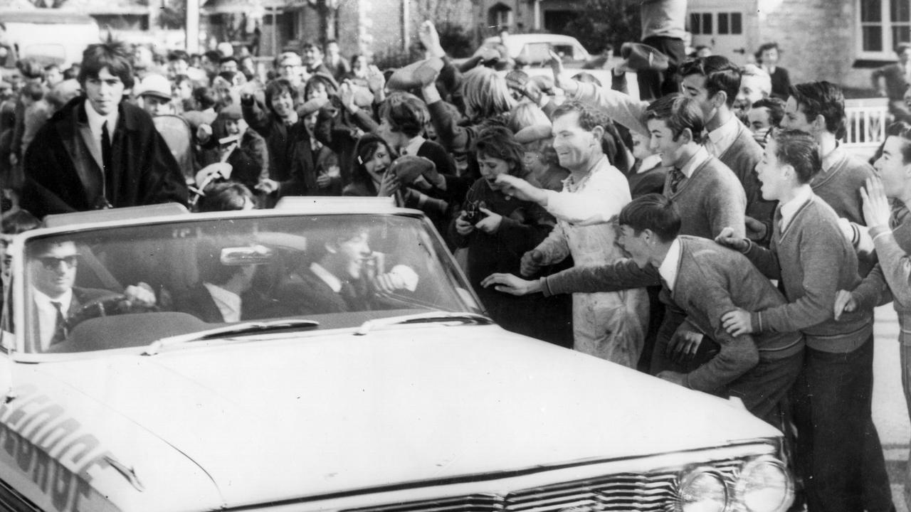 Workmen and schoolchildren in Adelaide mob the car carrying British pop sensation The Beatles while touring Australia in 1964. Picture: Keystone/Getty