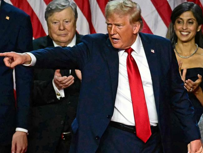 TOPSHOT - Former US President and Republican presidential candidate Donald Trump gestures at supporters after speaking as he holds hands with former US First Lady Melania Trump during an election night event at the West Palm Beach Convention Center in West Palm Beach, Florida, early on November 6, 2024. Republican former president Donald Trump closed in on a new term in the White House early November 6, 2024, just needing a handful of electoral votes to defeat Democratic Vice President Kamala Harris. (Photo by Jim WATSON / AFP)