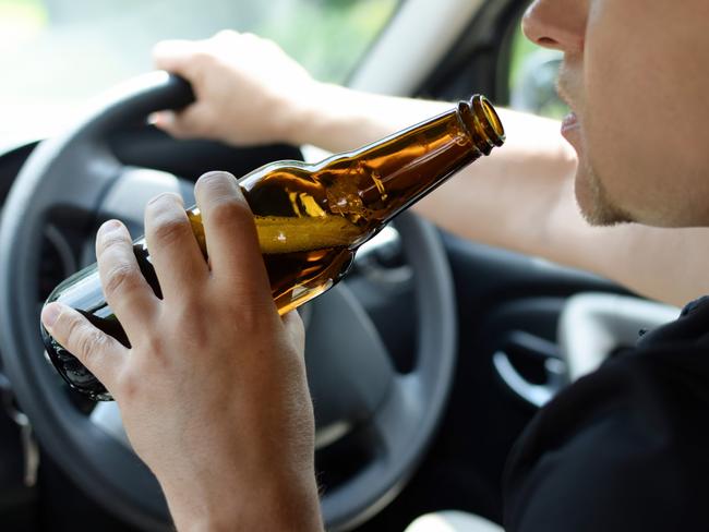 The concept of alcohol driving crime - closeup of young male driver hands with steering wheel and bottle of beer. Drink driving generic. Picture: iSTOCK