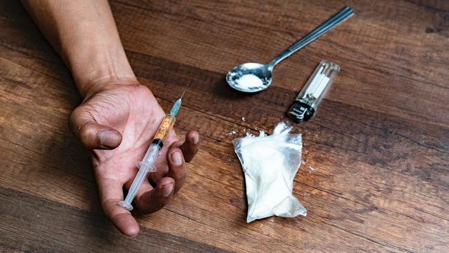 Human hand of a drug addict and a syringe with narcotic syringe lying on the floor. Anti drug concept.