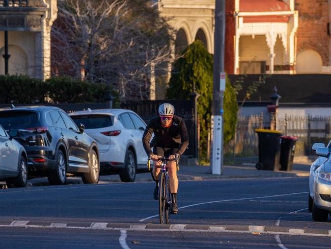 Winter afternoon in Fitzroy at Edinburgh Gardens with Victorian two story heritage houses against Melbourne high-rise CBD skyline, cars parked along suburban street with cyclist. Picture: Jason Edwards