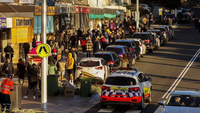 A police car drives past a strip of cafes packed with people at Bronte Beach, despite Sydney’s worsening Covid crisis. Picture: Jenny Evans/Getty Images