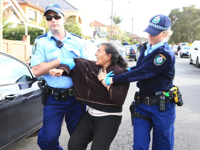 Police arrest Mary Bobolas after an alleged assault when the family refused to leave their house after a council-ordered $60,00 clean up. Picture: Adam Taylor