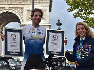 British cyclist Mark Beaumont (C) poses for pictures with Guinness World Records certificates after arriving at the Arc de Triomphe in Paris on September 18, 2017 to complete his tour around the world in 78 days. British adventurer Mark Beaumont bettered the fictional exploits of Phileas Fogg -- by going around the world in under 80 days on a bicycle. The 34-year-old Scotsman set a new world record for circumnavigating the globe on a bike when he arrived at the Arc de Triomphe in Paris on the night of September 18, 78 days after setting out from the landmark in the centre of the French capital.  / AFP PHOTO / CHRISTOPHE ARCHAMBAULT