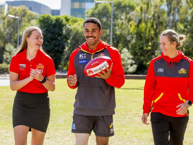 Touk Miller will play his 100th game for the Gold Coast Suns this Saturday. AFLW suns players, Charlotte Hammons and Tori Groves-Little with Touk Miller. Picture: Jerad Williams