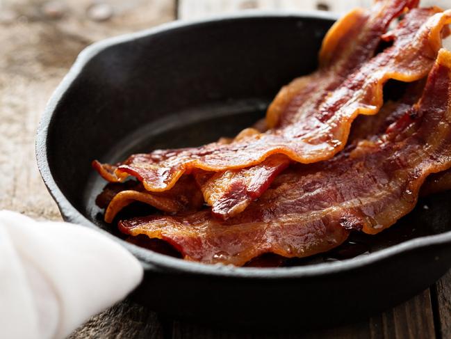 Sizzling hot bacon pieces in a cast iron skillet