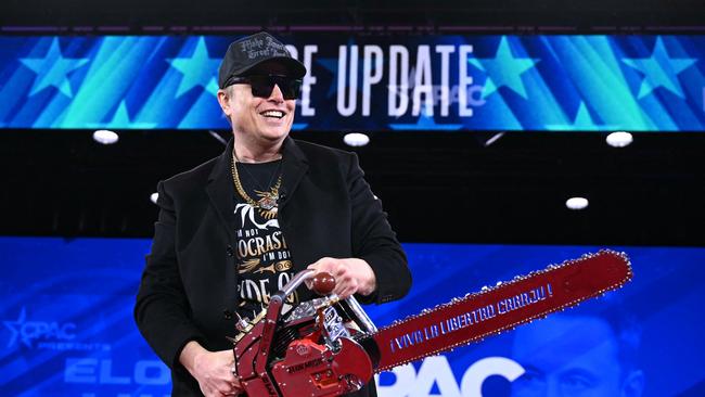 Elon Musk holds a chainsaw reading 