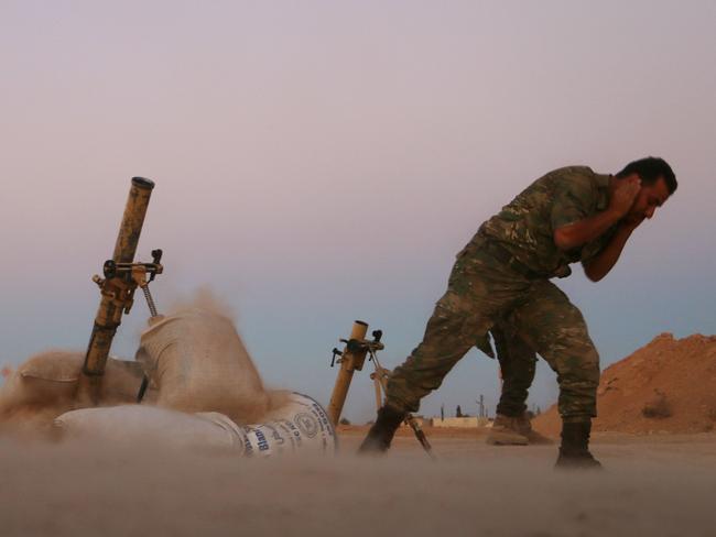 A fighter with the Free Syrian Army covers his ears as he fires a mortar launcher against Islamic State. Picture: AFP