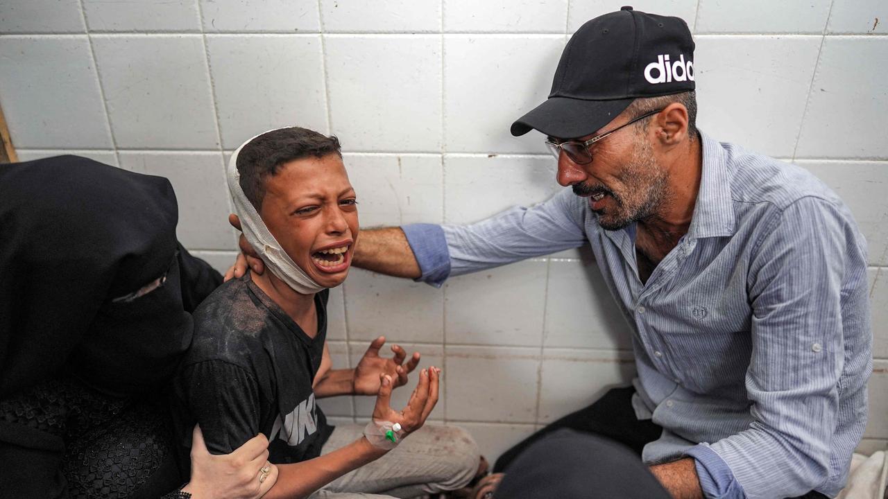 A woman and a man comfort an injured boy mourning the loss of his father who was killed in the aftermath of overnight Israeli bombardment. Picture: AFP)