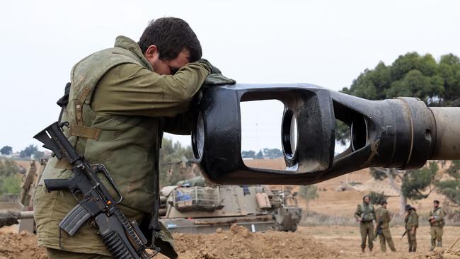 An Israeli soldier rests his head on an artillery gun barrel of an armoured vehicle as Israeli soldiers take positions near the border with Gaza in southern Israel. Picture: Jack Guez/AFP