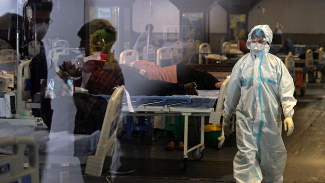 A health worker walks past COVID-19 coronavirus patients inside a banquet hall temporarily converted into a Covid care centre in New Delhi. Picture: AFP.