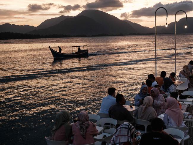 People enjoy dinner at an oceanfront cafe built on the site where houses were destroyed in Banda Aceh. Picture: AFP