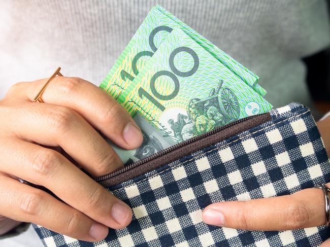 Woman put dollar australia money into wallet.