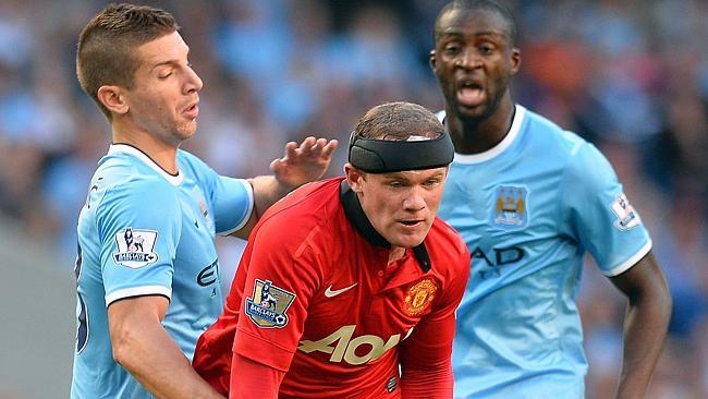 Manchester City's Ivorian Yaya Toure tackles Manchester United striker Wayne Rooney.